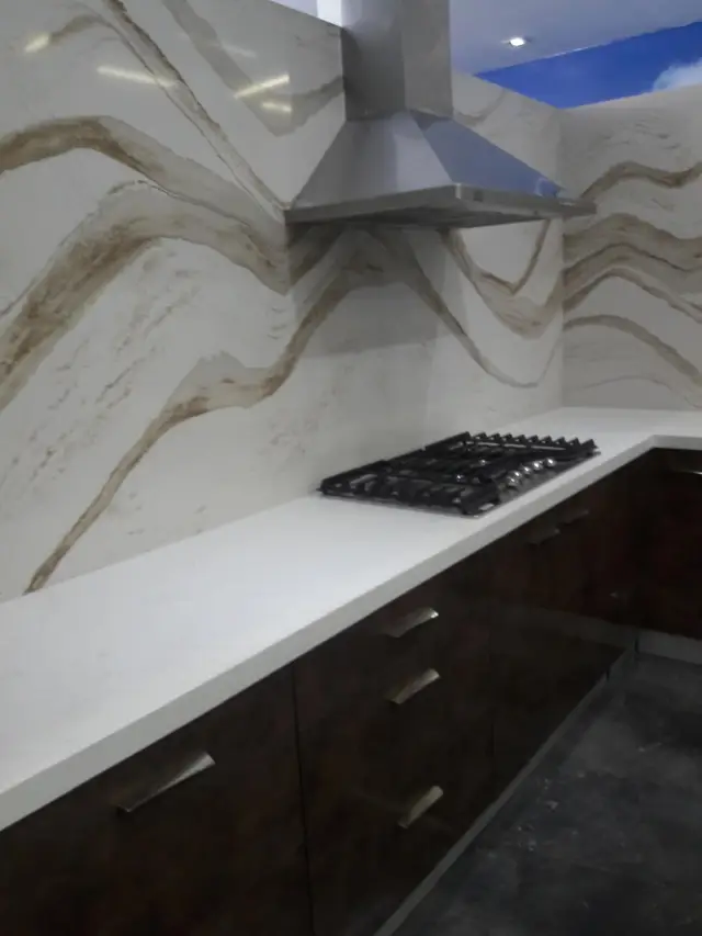 Kitchen with sculptural marble backsplash and range hood